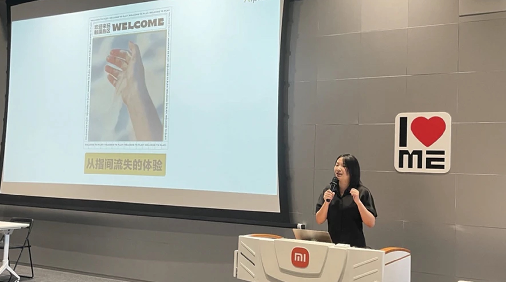 Presenting the study on stage at Xiaomi, standing at a Mi lectern with a microphone in front of a large screen showing the research deck's welcome slide